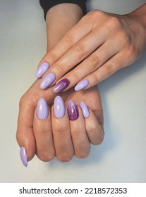 Beautiful purple manicure and shiny gradient design  Woman hands and long round nails   lilac gel polish