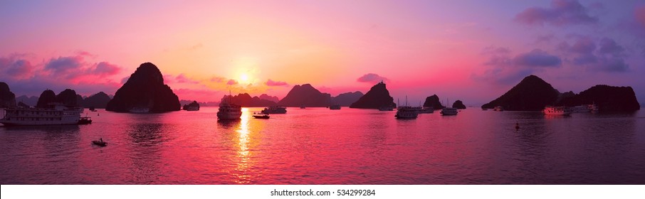Красивый фиолетовый закат и скальные острова в бухте Халонг Вьетнам Юго-Восточной Азии. Панорама. Круиз на лодке в бухту Халонг. Экзотические пейзажи. Панорамный вид. Пейзаж Розовое небо. Знаменитая достопримечательность Вьетнама