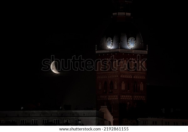 Beautiful quarter moon over Riga
old town behind Domes cathedral clock. Night sky with amazing
moon.