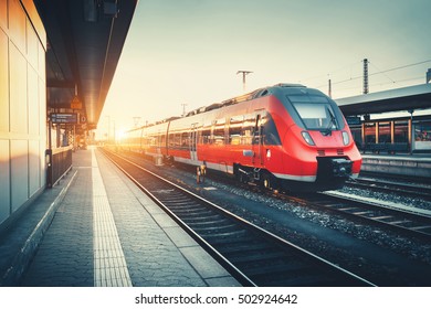 Beautiful Railway Station With Modern High Speed Red Commuter Train At Colorful Sunset. Railroad With Vintage Toning. Train At Railway Platform. Industrial Concept. Railway Tourism