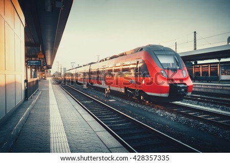 Beautiful railway station with modern red commuter train at colorful sunset in Nuremberg   , Germany. Railroad with vintage toning