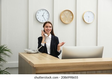 Beautiful Receptionist Talking On Phone At Counter In Hotel