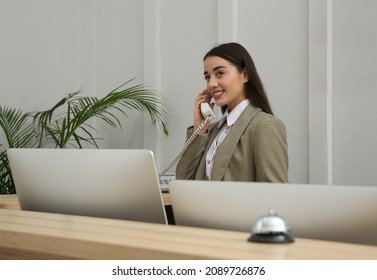 Beautiful Receptionist Talking On Phone At Counter In Hotel