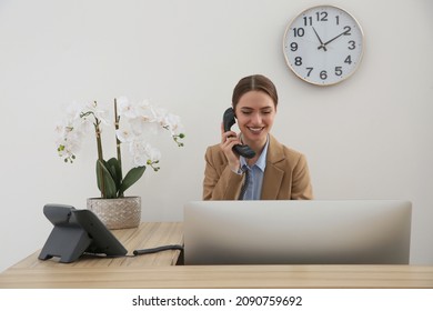 Beautiful receptionist talking on phone at counter in hotel