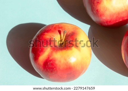 Beautiful red apples on a blue background. Bright shadow from sunlight. Sunlight falls on the apples creating a hard shadow. Useful fruits - apples.