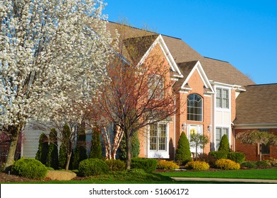 A Beautiful Red Brick Upscale Home In The Early Spring With Flowering Tree