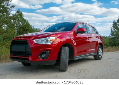 Beautiful red car on road in forest in background.