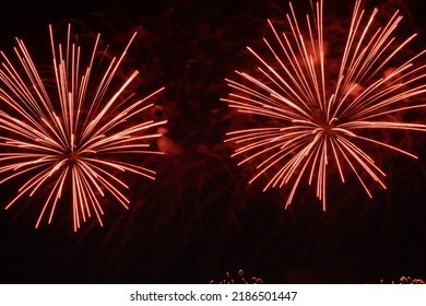 Beautiful Red Fireworks On The Night Sky, Amazing Holiday Fireworks Party Or Any Holiday Event. Fireworks Celebration Happy New Year