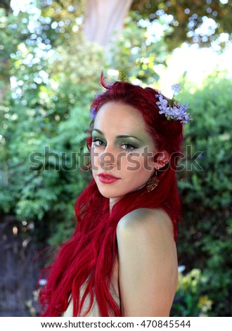 beautiful red haired woman with flowers in her hair, natural background.