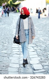 Beautiful Red Haired Woman Wearing Oversized Coat, Boyfriend High Waisted Jeans, Black Scarf, Leather Bag And Boots, Posing Outdoors. Street Style.