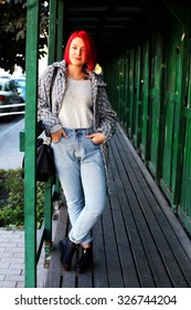 Beautiful Red Haired Woman Wearing Oversized Coat, Boyfriend High Waisted Jeans, Black Scarf, Leather Bag And Boots, Posing Outdoors. Street Style.