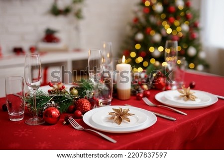 Beautiful red table with plates and champagne glasses for family christmas dinner