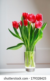 Beautiful Red Tulips In Vase Over White Wall