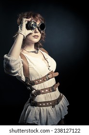 Beautiful Redhair Steampunk Woman Looking Over Her Goggles Aside On The Black Backgroud