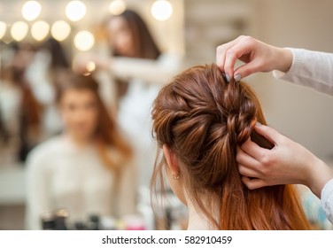 Beautiful, red-haired girl with long hair, hairdresser weaves a French braid, in a beauty salon. Professional hair care and creating hairstyles. - Shutterstock ID 582910459