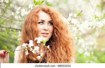 Beautiful Red-haired Woman With Freckles And Spring Cherry Blossoms