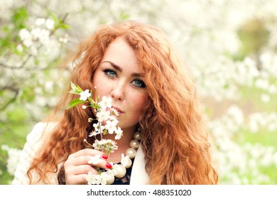 Beautiful Red-haired Woman With Freckles And Spring Cherry Blossoms