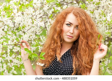 Beautiful Red-haired Woman With Freckles And Spring Cherry Blossoms