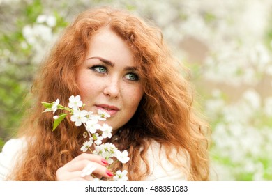 Beautiful Red-haired Woman With Freckles And Spring Cherry Blossoms