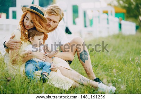 Beautiful red-haired woman with her husband and a wonderful son on a summer park