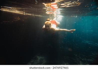 Beautiful red-haired woman swims underwater in the pool. - Powered by Shutterstock