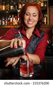 Beautiful redhead barmaid making cocktail