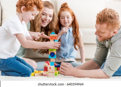 beautiful redhead family playing with constructor on floor at home, family fun at home concept