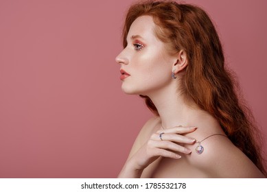 Beautiful Redhead Freckled Woman With Bold Pink Eyes Makeup, Wearing Stylish Jewelry: Earrings, Rings, Necklace, Posing In Studio. Jewellery Advertising Conception. Copy, Empty Space For Text