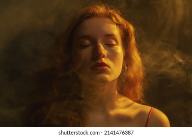 Beautiful Redhead Freckled Woman Posing In Darkness, Smoke And Warm Light. Art Studio Portrait. Copy, Empty Space For Text
