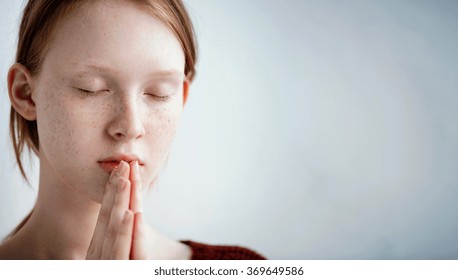 Beautiful Redhead Freckled Young Teen Girl Prays. Close Up Portrait Of A Female Praying