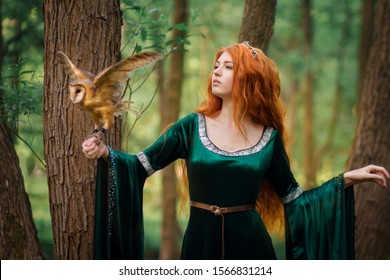 Beautiful redhead girl in green dress with owl on her hand