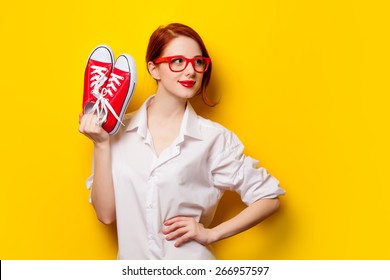 Beautiful Redhead Girl In White Shirt With Gumshoes On Yellow Background.