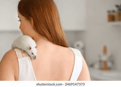 Beautiful redhead woman with cute rat in kitchen, back view - Powered by Shutterstock