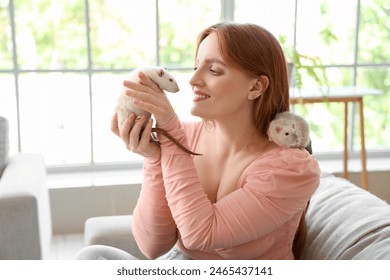 Beautiful redhead woman with cute rats sitting on sofa at home - Powered by Shutterstock