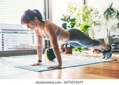 Beautiful redhead woman's home fitness routine. Home workout on gym mt in living room, sporty woman wearing sportswear. - Powered by Shutterstock