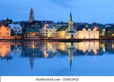 Beautiful reflection of the cityscape of Reykjavik in lake Tjornin at the blue hour in winter