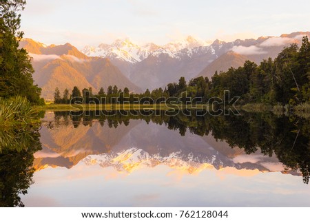 Beautiful reflection of mountain and trees in lake Matheson, South Newzealand.