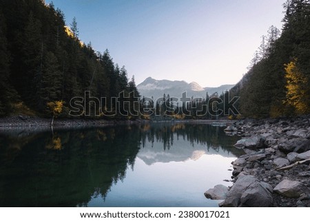  A beautiful reflection on a sunny afternoon in autumn with a mountain background, colorful fall foliage, rocks, and trees at Lindeman Lake in Chilliwack Lake Provincial Park, British Columbia, Canada