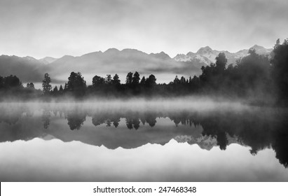 Beautiful reflections of Southern Alps at Lake Matheson, New Zealand, in the early morning mist, in black and white.