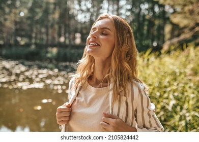 Beautiful relaxed long-haired woman on a river bank - Shutterstock ID 2105824442