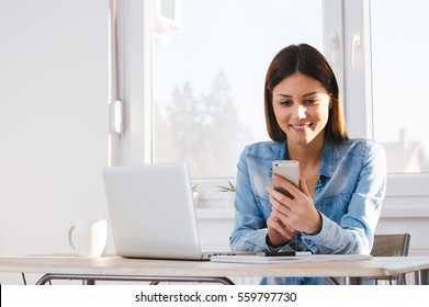 Beautiful Relaxed Student Learning With Laptop And Texting In A Mobile Phone 