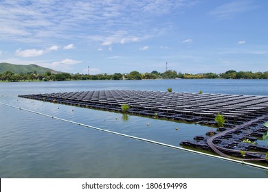 Beautiful renewable natural energy landscape photo under bright sky of Floating Solar Cells panel in fresh water at the big public park lake in with small hill and telecommunication poles in  Thailand