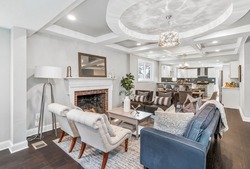 BEAUTIFUL RENOVATION WITH COFFERED CEILING SHOWING LIVING ROOM WITH BRICK FIREPLACE. STAGED HOME WITH ELEGANT LIGHT FIXTURE AND CONTEMPORARY FURNISHING IN INTERIOR RESIDENTIAL HOME