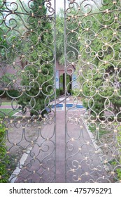 Beautiful retro and classical design of wrought iron brass gate and fence pattern with locked key, garden and road  background