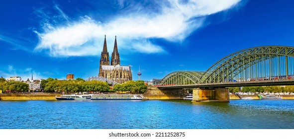 Beautiful rhine river skyline, medieval gothic dome, Hohenzollern bridge, dramatic deep blue summer sky, cruise ship - Cologne, Germany 