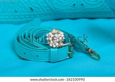 Beautiful ring of pearl and handbag on blue background