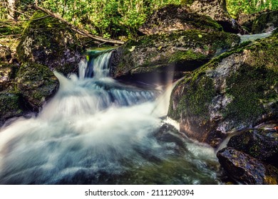 Beautiful River With Flowing Water, Rapids, Rocks Moss And Forest In Background, Long Exposure In Volda, Norway