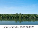 Beautiful river scenery. The wide mouth of the Danube River. On the other bank a green forest. Clear blue sky. 