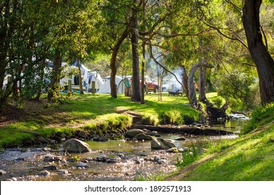  The Beautiful Riverbank Of A Small Flowing River With Some Camping Tents And Fire Pits In The Background. Concept Of Outdoor Adventure, Family Holiday And Summer Holiday Fun. Wye River, VIC Australia