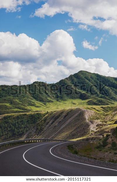 A\
beautiful road high in the mountains at the pass. Landscape of the\
Altai Republic in the summer. Vertical photo of\
nature.